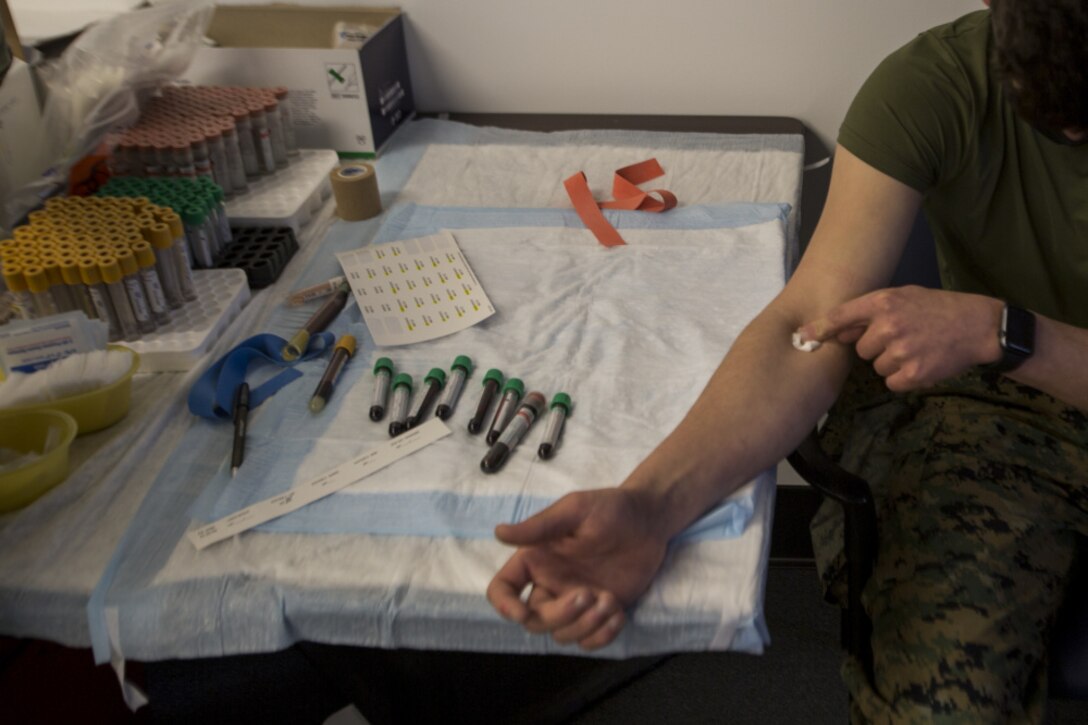 A U.S. Marine participant with the COVID-19 Health Action Response for Marines (CHARM) study covers a needle hole after getting his blood sample collected on Camp Johnson, N.C., Mar. 3, 2021.