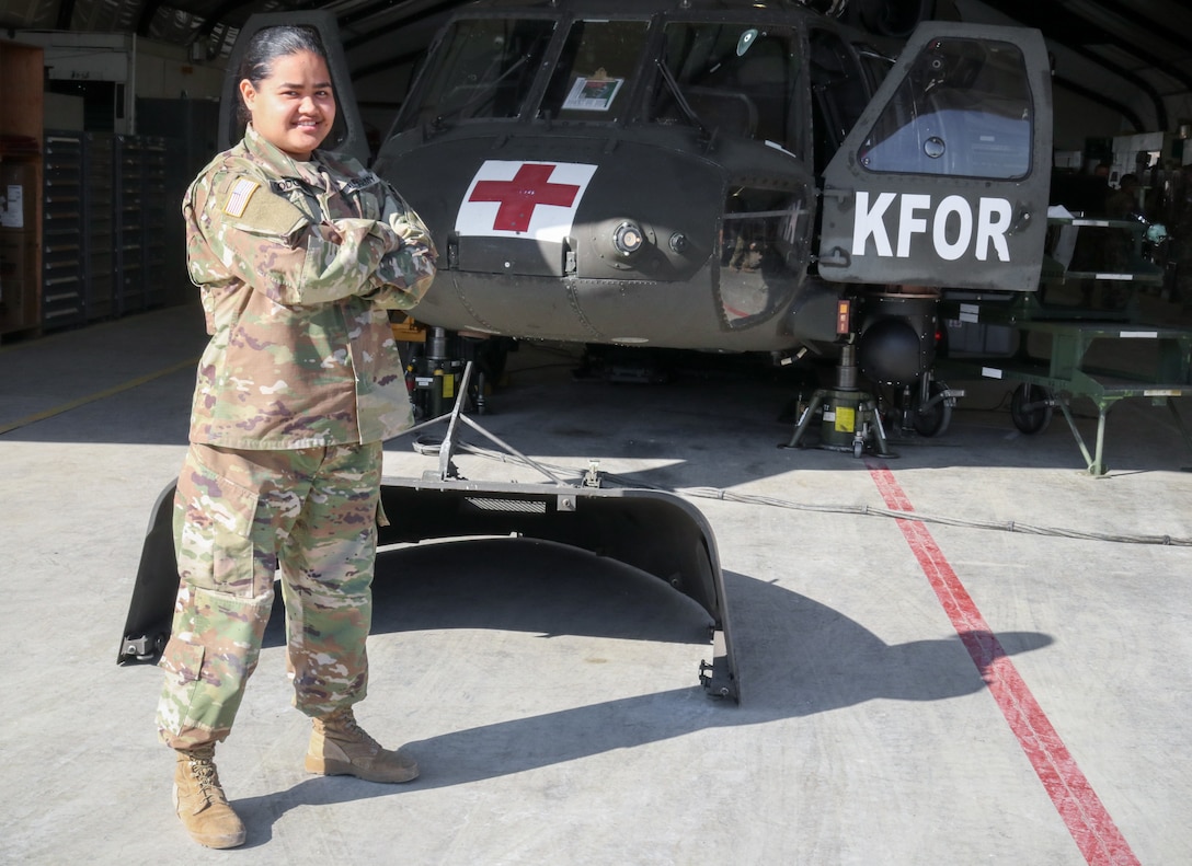 Pfc. Genevieve Godgow, an aircraft structural repairer attached to 3rd Battalion, 238th General Support Aviation Battalion, Delaware Army National Guard, smiles for a picture in front of a UH-60 Blackhawk at Camp Bondsteel, Kosovo, on March 3, 2021.