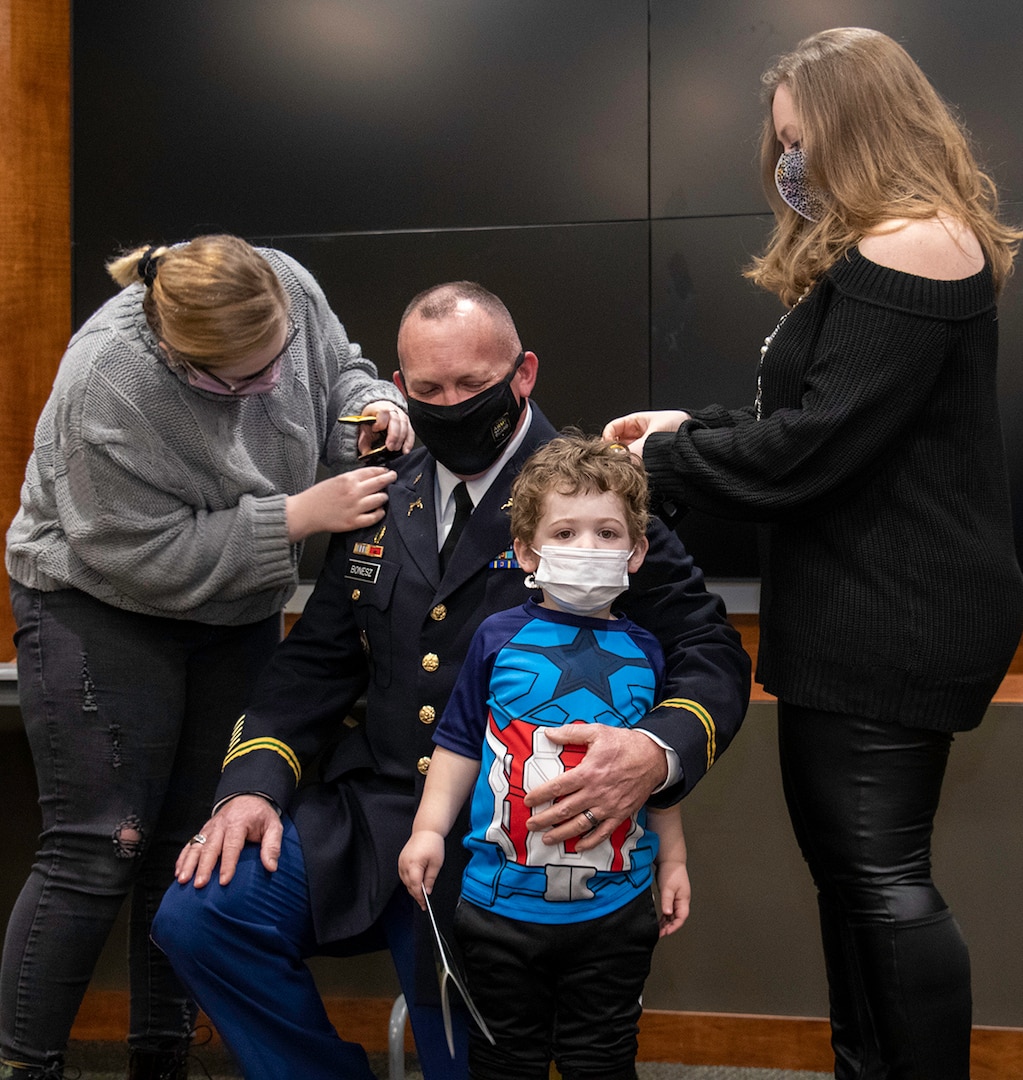 Newly promoted Col. Ronald W. Bonesz’s daughter, Melanie (left), son Lucas (standing) and wife, Blair, place his new rank on during a promotion ceremony Feb. 26 at Camp Lincoln in Springfield, Illinois.