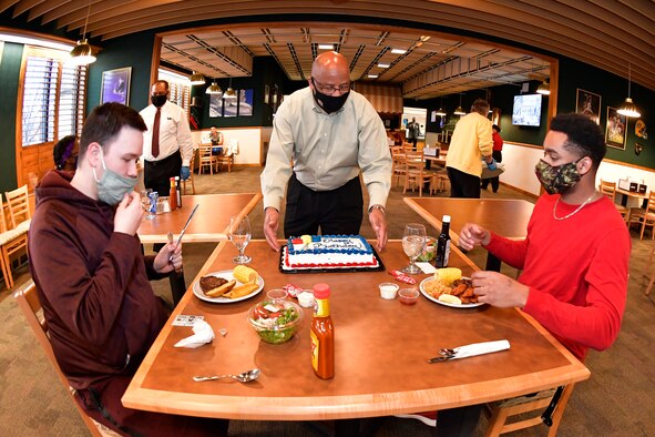 Airman 1st Class Dawson Sigetti (left) and Airman 1st Class John Moore, both with 75th Force Support Squadron, are served a birthday cake by Moses Thompson, 75th FSS Sustainment Flight chief, at the Hillcrest Dining Facility March 3, 2021, at Hill Air Force Base , Utah. A new birthday meal program was introduced to allow dorm residents and guest to celebrate by receiving a special no-cost birthday meal and cake at the dining facility. (U.S. Air Force photo by Todd Cromar)