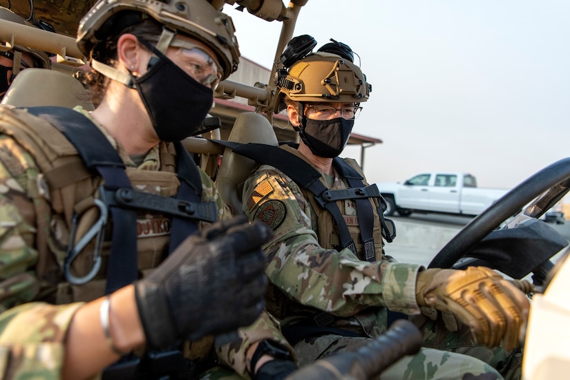 A sergeant and a general drive an all-terrain vehicle.