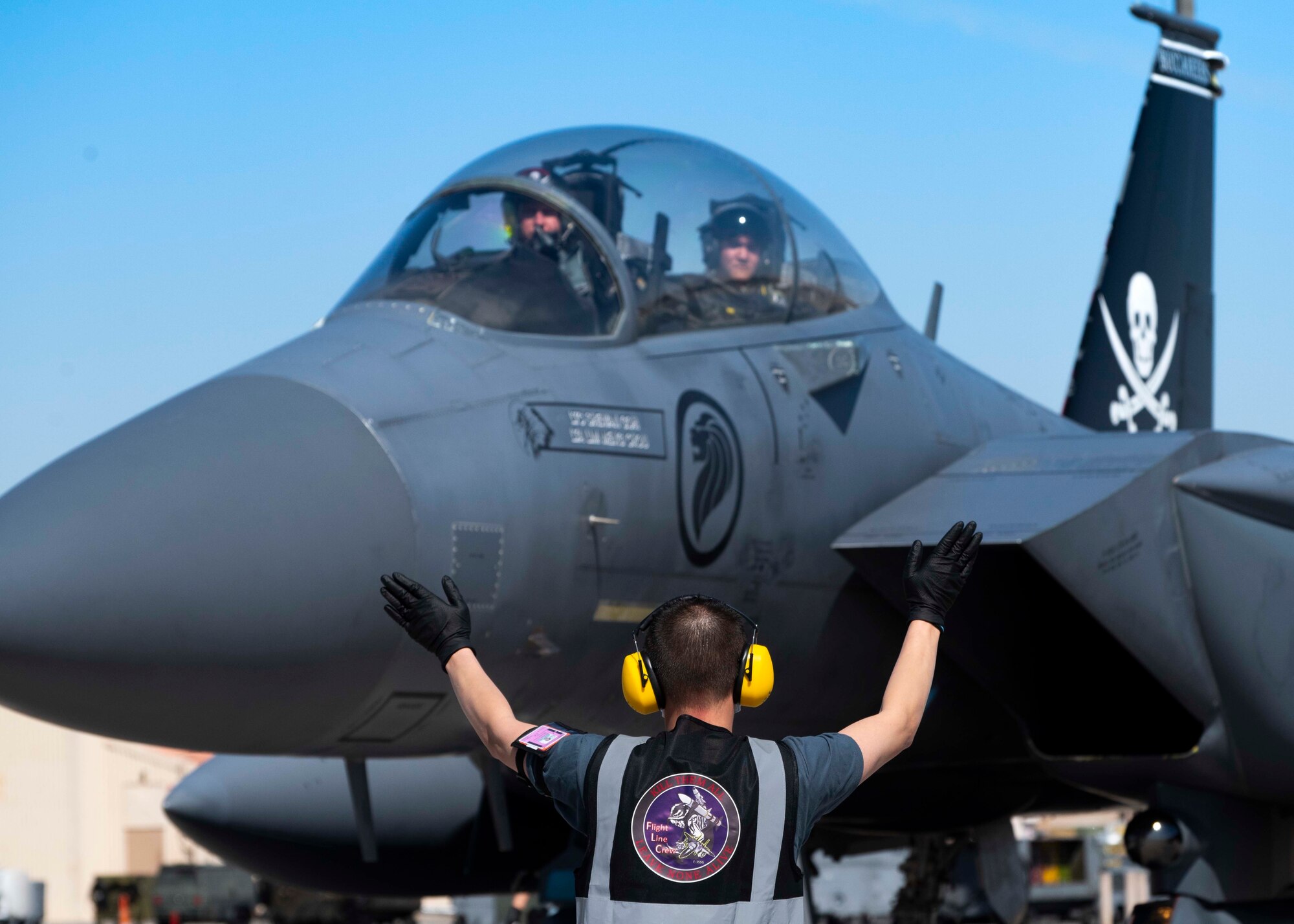 A crew chief from the 428th Fighter Squadron marshals an F-15SG Strike Eagle on the flightline.