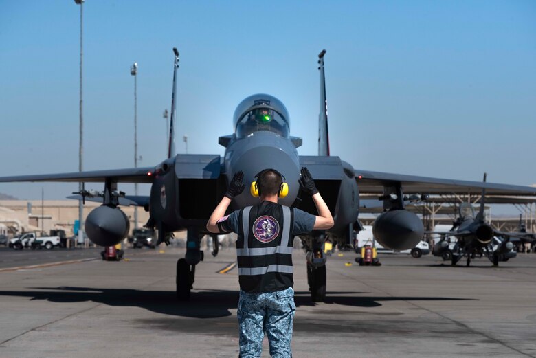 A crew chief from the 428th Fighter Squadron marshals an F-15SG Strike Eagle on the flightline.