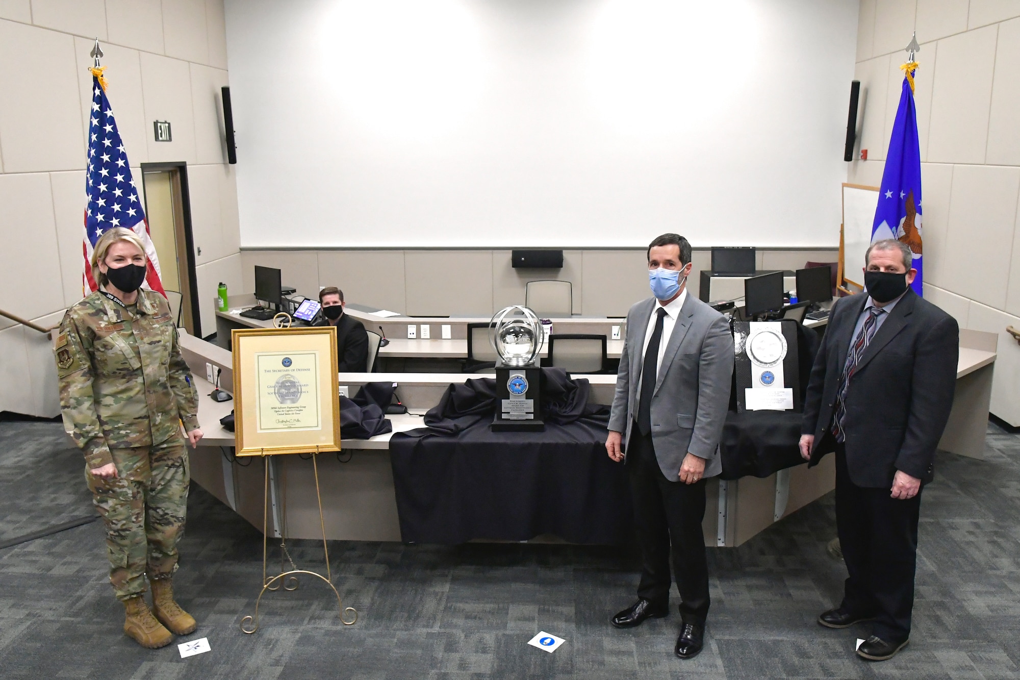 (Left to right) Brig. Gen. Cauley von Hoffman, Ogden Air Logistics Complex commander, Steven J. Morani, Principal Deputy Assistant Secretary of Defense for Logistics, and Jim Diamond, 309th Software Engineering Group director, stand for a photo during the presentation of the 2020 Rear Admiral Grace M. Hopper Award. The award trophy sits on a table behind them.