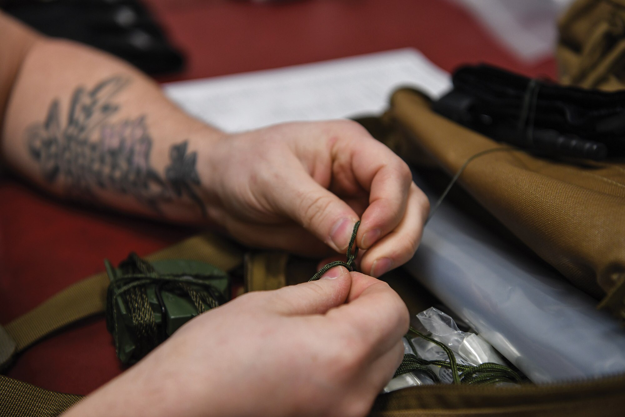 Staff Sgt. Brett Schindler, 445th Operations Support Squadron, aircrew flight equipment shop NCO in charge of helmets and chemical defense gear section, ties a lanyard to secure an escape and evasion kit inside an aircrew survival backpack at Wright-Patterson Air Force Base, Ohio Feb 12, 2021. The gear is used for aircrew survival during an emergency when they need to evacuate the aircraft.