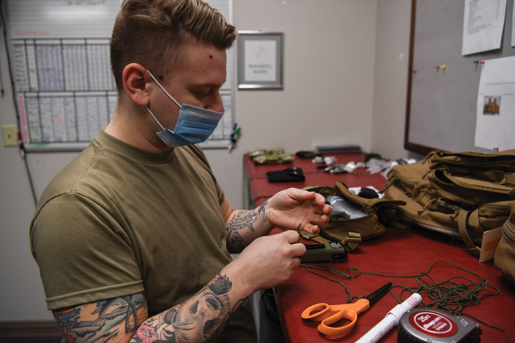 Staff Sgt. Brett Schindler, 445th Operations Support Squadron, aircrew flight equipment shop NCO in charge of helmets and chemical defense gear section, ties a lanyard to secure an escape and evasion kit inside an aircrew survival backpack at Wright-Patterson Air Force Base, Ohio Feb 12, 2021. The gear is used for aircrew survival during an emergency when they need to evacuate the aircraft.