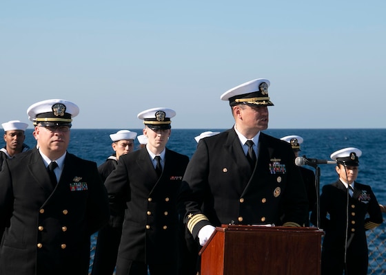 210304-N-RG171-0261 MEDITERRANEAN SEA (Mar. 4, 2021) Cmdr. Matthew Curnen, commanding officer of the Arleigh Burke-class guided-missile destroyer USS Donald Cook (DDG 75), front right, speaks during a burial-at-sea, Mar. 4, 2021. Donald Cook, forward-deployed to Rota, Spain, is on patrol in the U.S. Sixth Fleet area of operations in support of regional allies and partners and U.S. national security in Europe and Africa. (U.S. Navy photo by Machinist’s Mate 1st Class Peter Stitzel/Released)