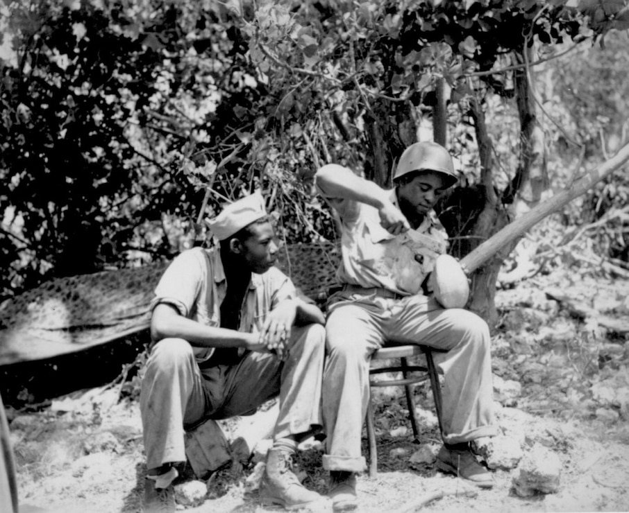 Marine Sgt. F. Smit and Cpl. S. Brown open a coconut to get a cool drink on Saipan, June 1944.