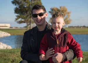 Senior Airman Anthony Gauna Jr. holds his son, Anthony Gauna III in front of Ike Skelton Lake.