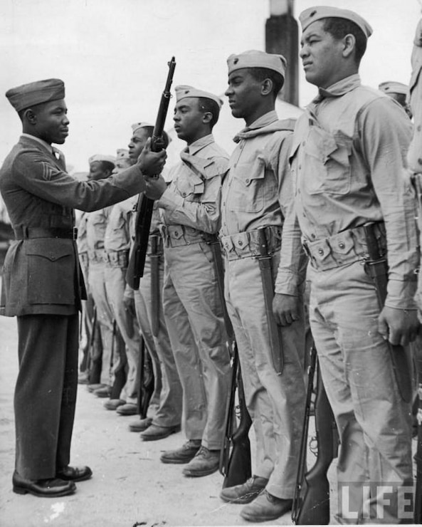 Marine Corps Cpl. Edgar R. Huff inspects a weapon at Montford Point Camp, Camp Lejeune, North Carolina. He enlisted in the Marine Corps in June 1942.