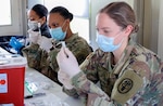 U.S. Army 1st Lt. Abigail Santora (right), a medical surgical nurse at Carl R. Darnall Army Medical Center, Fort Hood, Texas, and 2nd Lt. Sharice Jones (center), a medical surgical nurse at Brooke Army Medical Center, Joint Base San Antonio-Fort Sam Houston, work alongside Federal Emergency Management Agency volunteer medical staff to prepare COVID-19 vaccines at the Fair Park COVID-19 Community Vaccination Centers  in Dallas March 2.