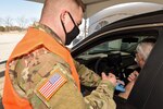 U.S. Army Spc. Samuel Meyer, a combat medic with the Michigan Army National Guard, administers the COVID-19 vaccine to a resident at Delta College, University City, Michigan, March 6, 2021. Michigan National Guard Soldiers and Airmen are helping local health officials deliver and administer the vaccine to Michiganders.