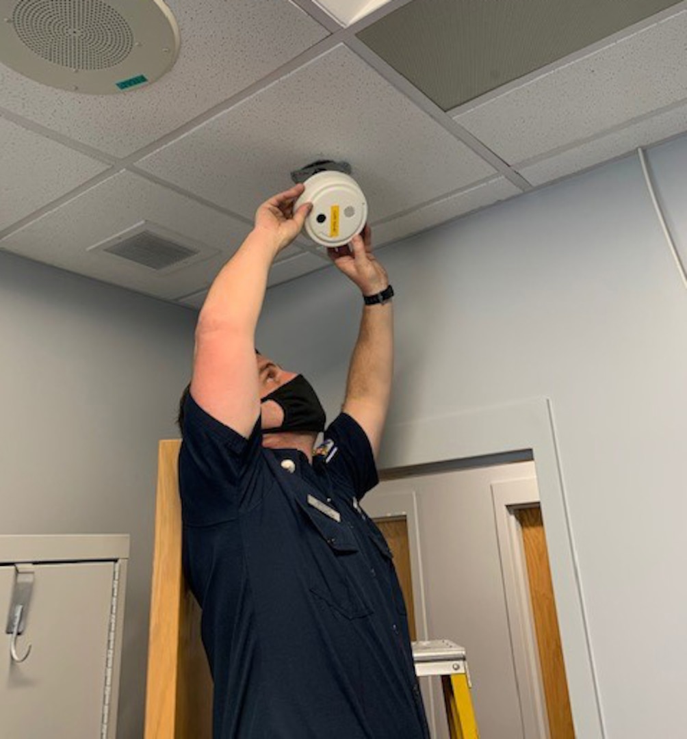 Fire Inspector Jamie MacFarlane removes a smoke detector to change its battery.