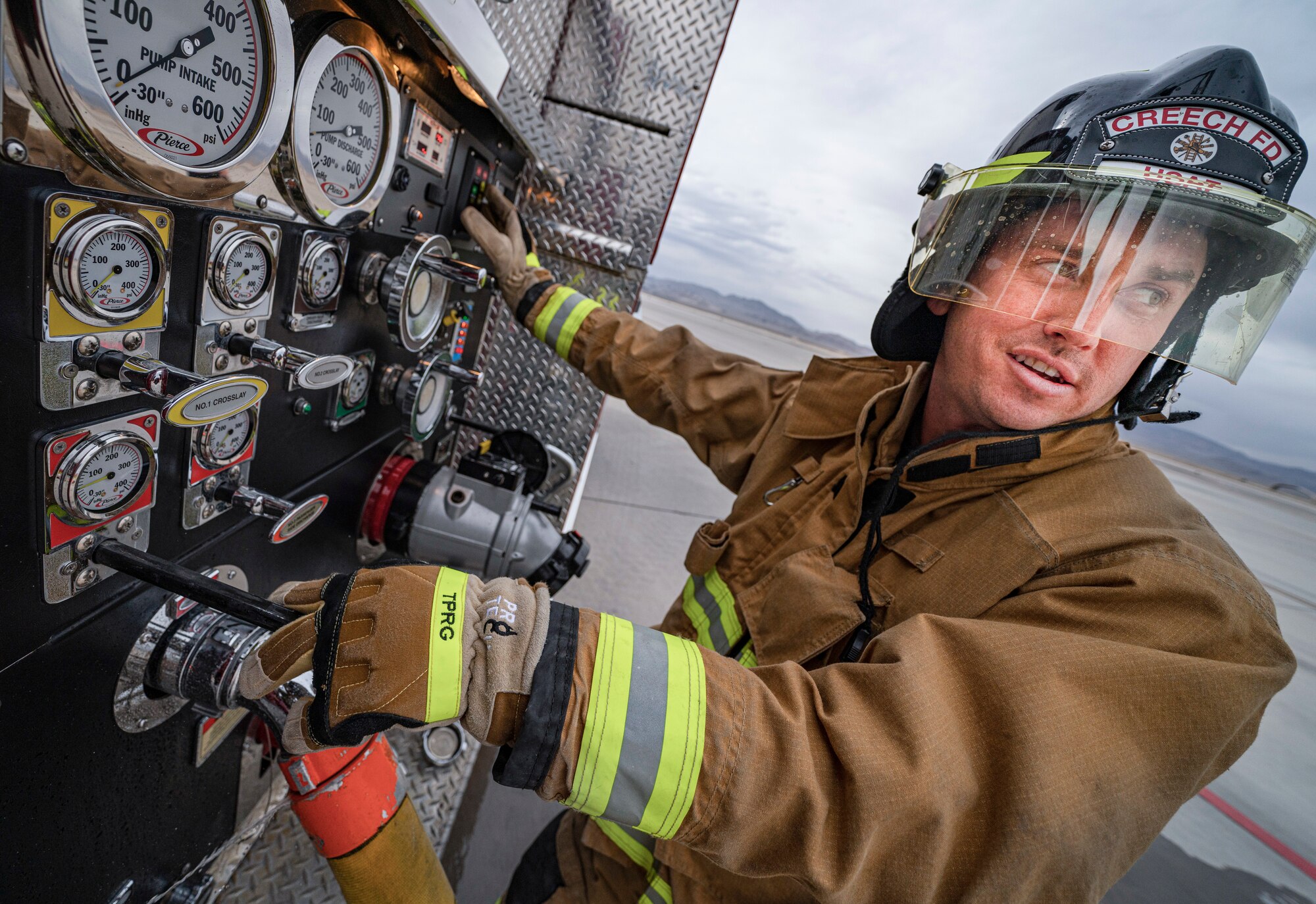 A member of the Creech Air Force Base Fire Department monitors water levels as its pumped into a fire engine.