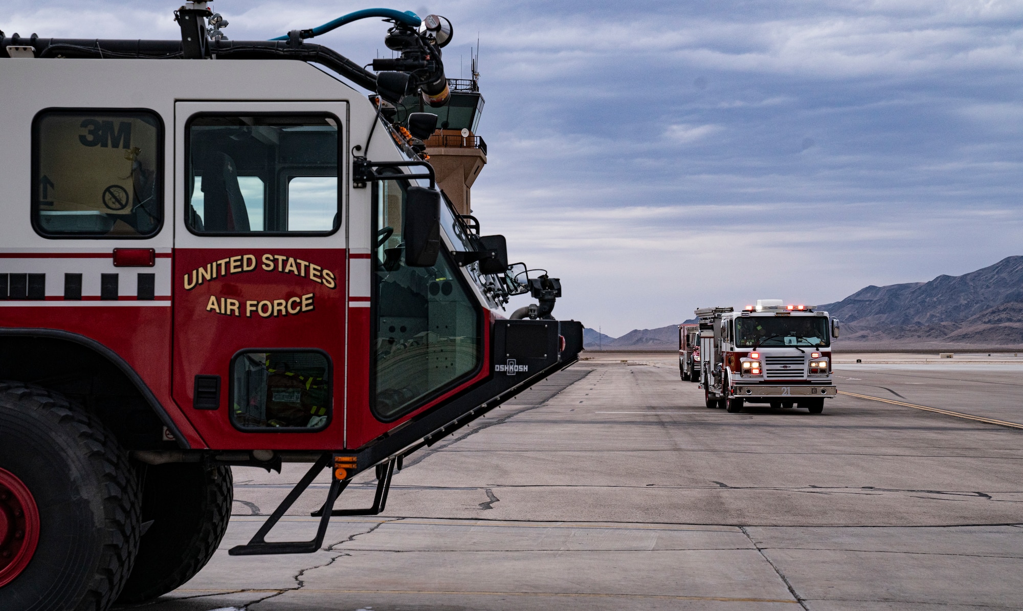 A Creech Air Force Base Fire Department tanker and fire engine drive on the flight line.