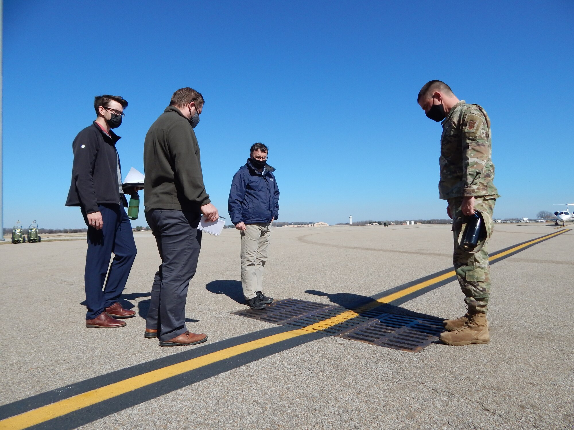 Lt. Col. Paul Fredin, commander of the 375th Civil Engineer Squadron, and 375th CES engineer Kenneth Cavanaugh (middle) talk with graduate students Kyle Collier and Cam Loyet (left to right) about water drainage on the flightline.  The students are taking the Innovating for Defense course at Washington University. They are working with Scott’s Elevate innovation team on identifying solutions to prevent future flooding of Hangar 3, which is used to house and maintain C-21 aircraft. (Photo by Christi Spargur)