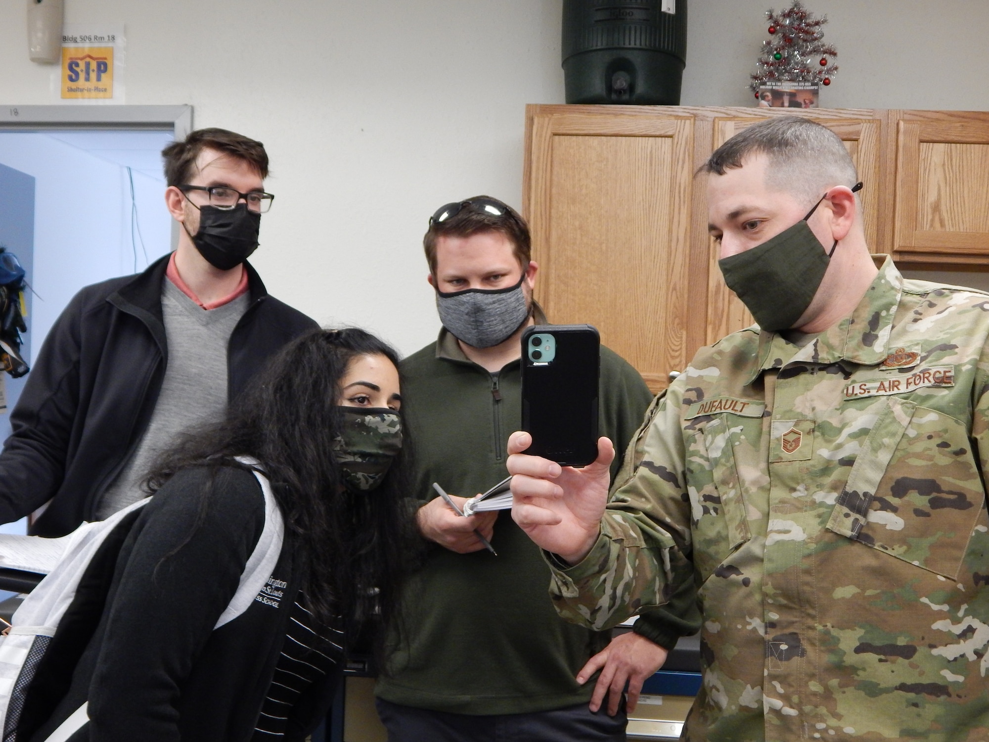 Master Sgt. Joseph Dufault, superintendent, Aircrew Flight Equipment, 375th Operations Support Squadron shows a video on his phone of the August 12, 2020, flooding of the AFE office to graduate students (left to right) Kyle Collier, Astha Bhatnagar, and Cam Loyet. The students are helping Scott’s Elevate innovation team to find potential solutions to prevent future flooding. (Photo by Christine Spargur)