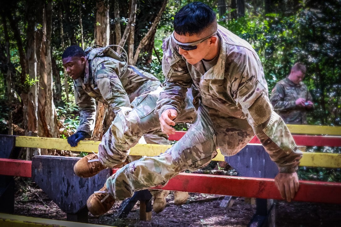 Soldiers leap over barriers in the jungle.