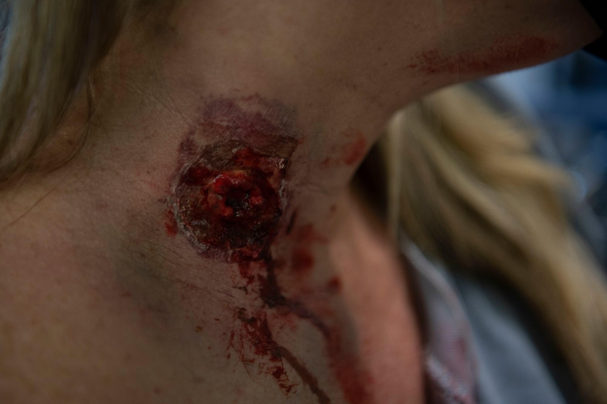 Marika Leegwater, moulage model, shows a mock gunshot wound in the neck during Advanced Trauma Life Support training March 4, 2021, Travis Air Force Base, California. ATLS equips different specialties in the medical field with the skills to treat traumatic injuries. (U.S. Air Force photo by Airman 1st Class Alexander Merchak)