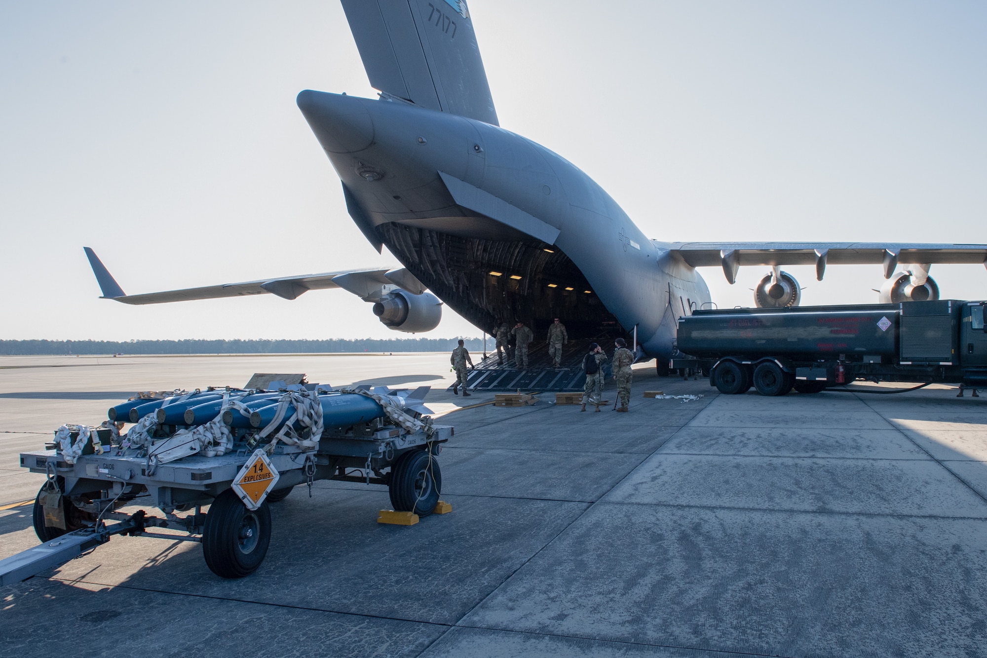 A photo of Airmen preparing to load a munitions trailer onto an aircraft