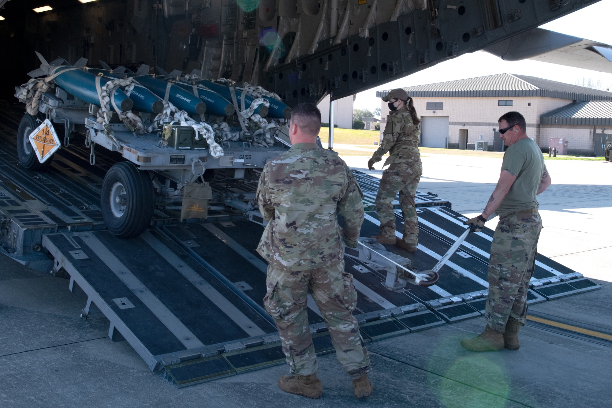 A photo of Airmen loading a munitions trailer onto an aircraft