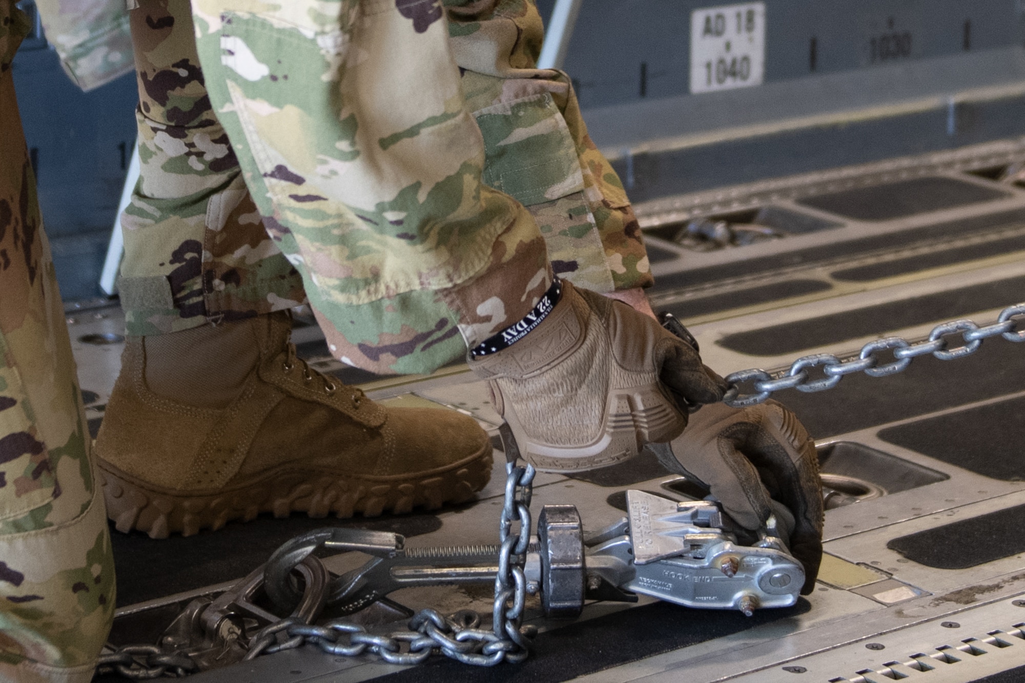 A photo of an Airman securing a munitions trailer onto an aircraft