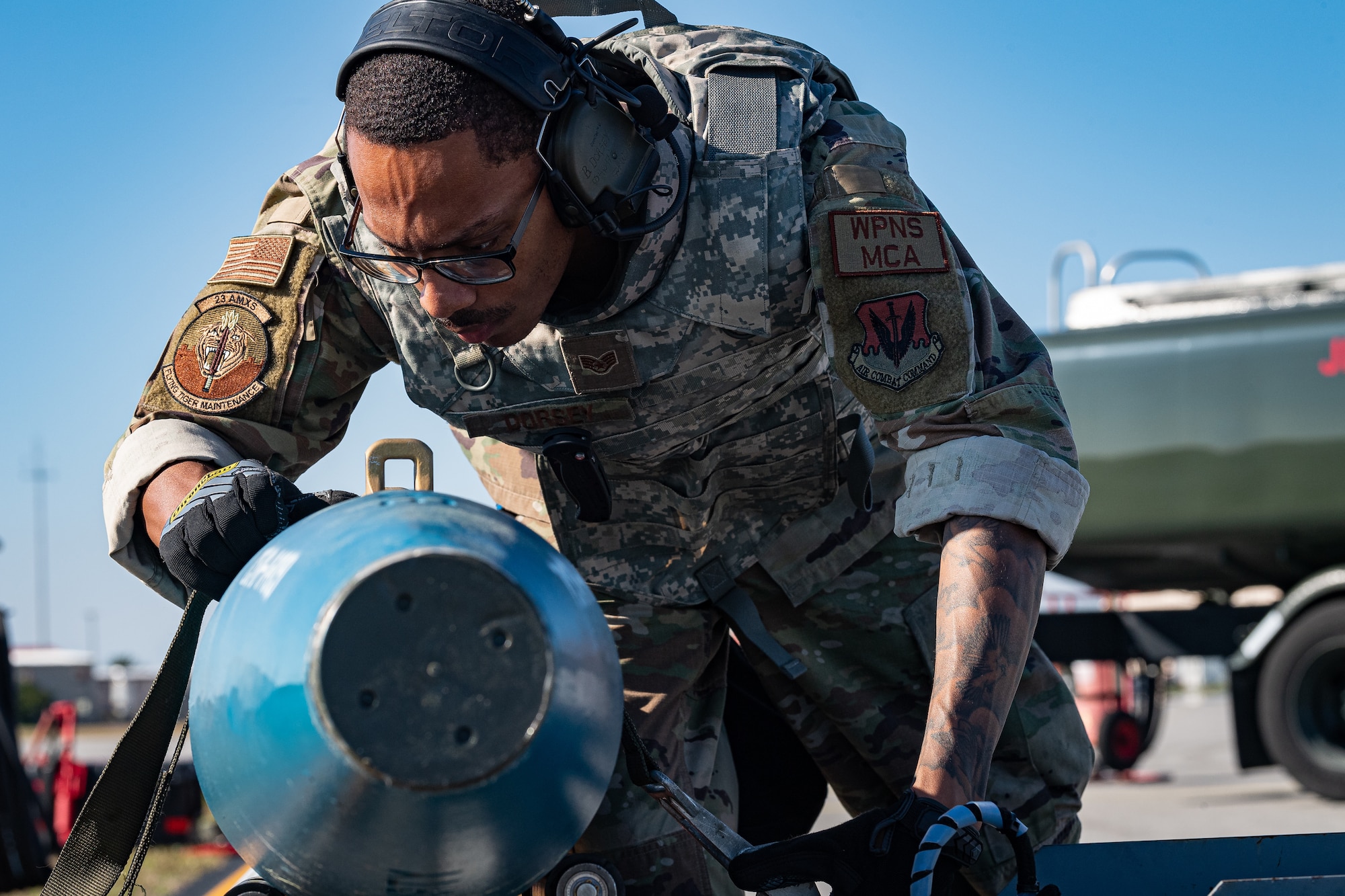 A photo of an Airman strapping a bomb to a weapons loader