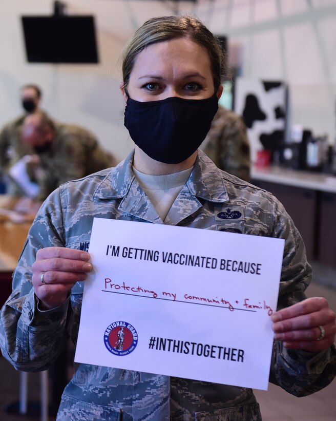 U.S. Air Force Staff Sgt. Kati Wilson, assigned to the Ohio Air National Guard's 178th Logistics Readiness, holding a sign depicting her reason for getting the COVID-19 vaccine, on base in Springfield, Ohio.