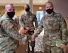 Two men in masks and uniform shake hands