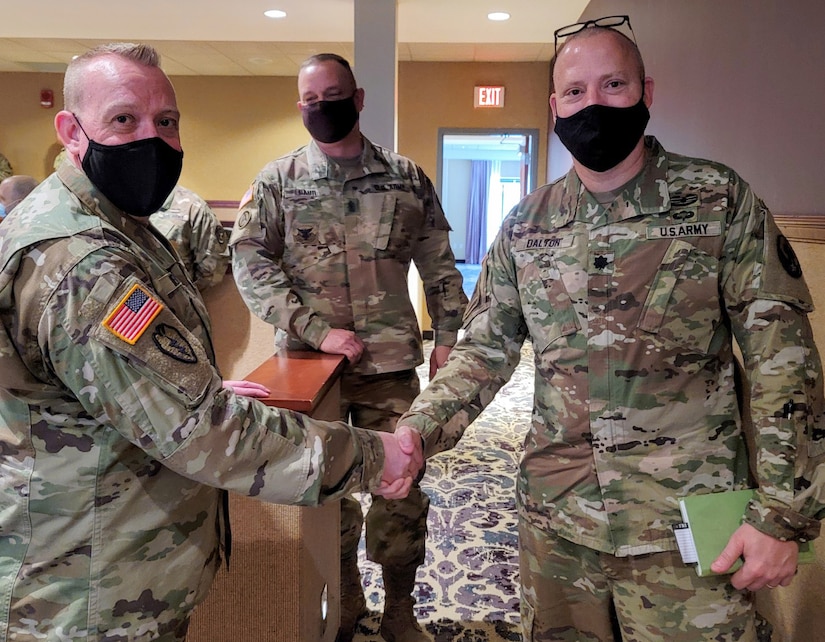 Two men in masks and uniform shake hands