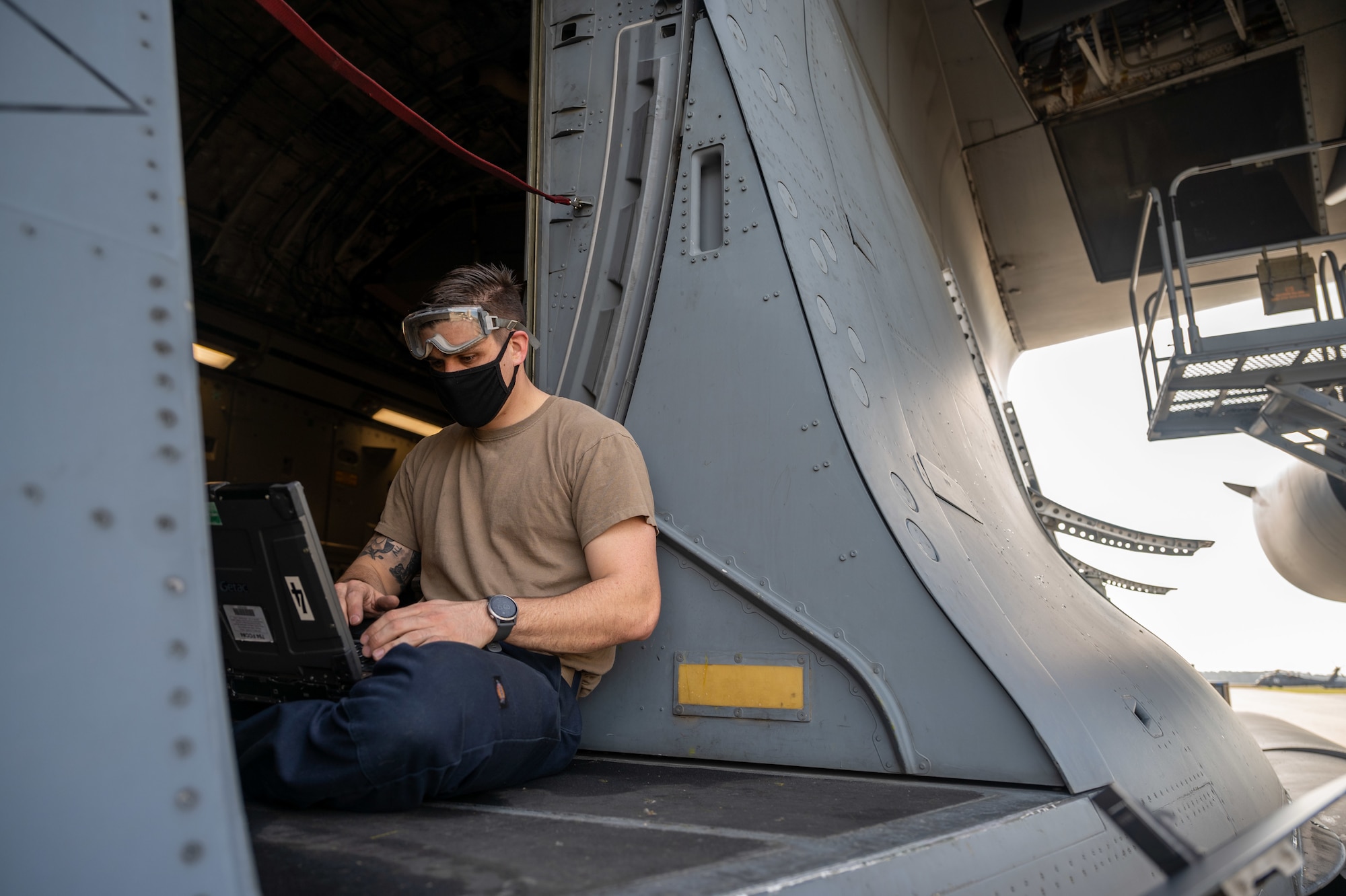 Staff Sgt. Timothy Clayton-Cornell, 736th Aircraft Maintenance Squadron crew chief, researches maintenance solutions next to an egress door on a Dover Air Force Base C-17 Globemaster III at Moody AFB, Georgia, Feb, 28, 2021. Aircrew from the 3rd Airlift Squadron identified a faulty plug housing on the C-17 following the completion of Exercise Mosaic Tiger. A three-Airmen Maintenance Recovery Team from Dover AFB was alerted and mobilized within 24 hours. The MRT, along with the flying crew chief assigned to the C-17, coordinated parts and tools from Joint Base Charleston, South Carolina, to ensure the successful return of the aircraft to Dover AFB. (U.S. Air Force photo by Airman 1st Class Faith Schaefer)
