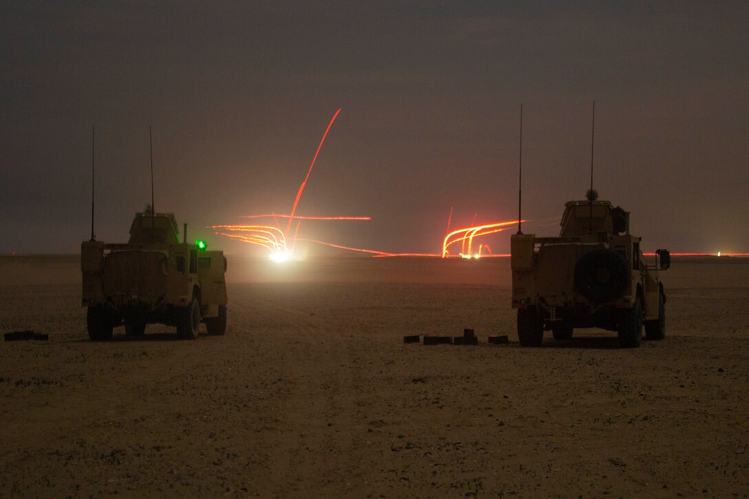 Streaks of light flash before two vehicles parked on dusty terrain at night.