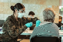 A U.S. Navy Hospital Corpsman administers a COVID-19 vaccine to a community member.