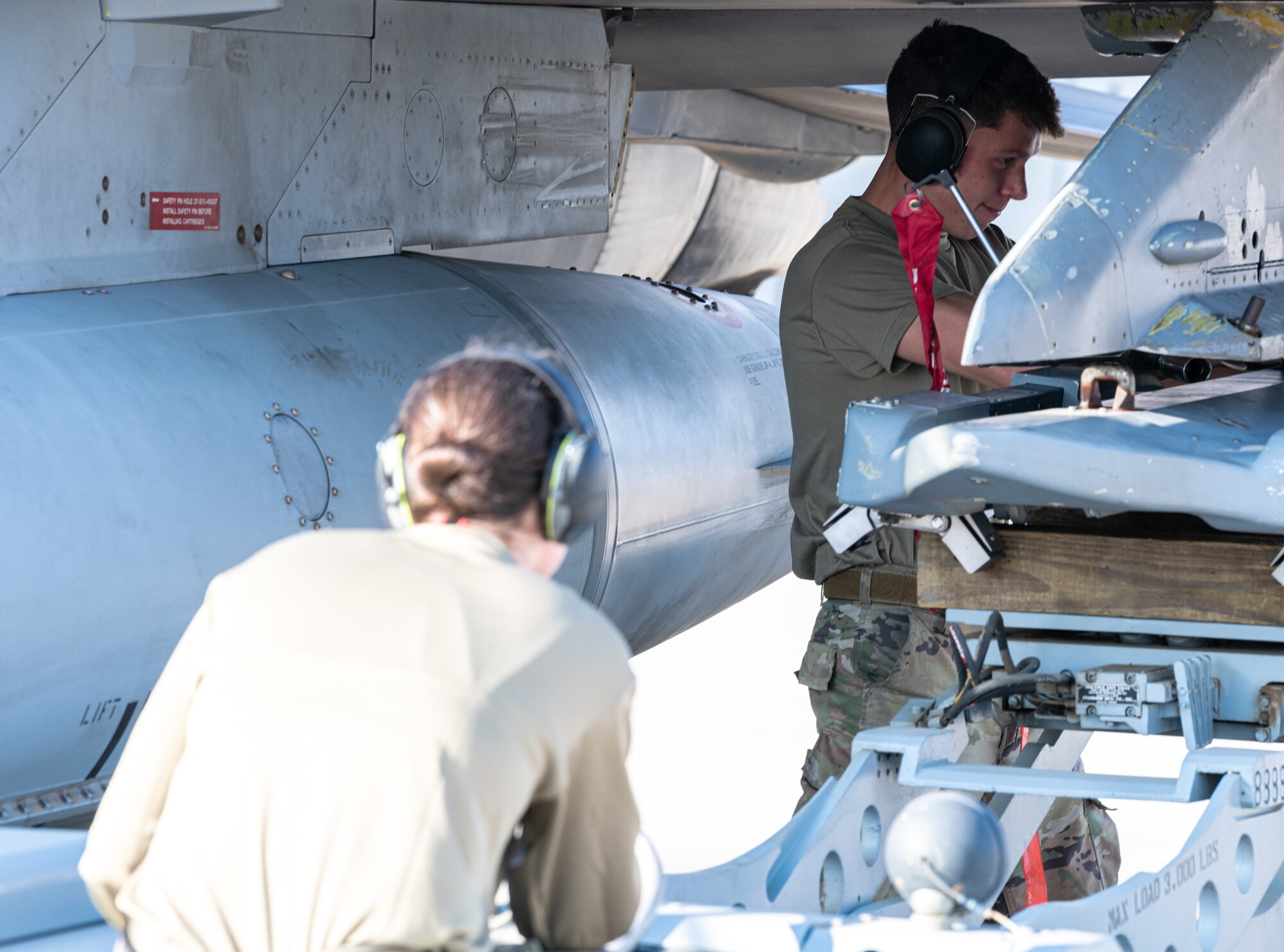 Senior Airman Ramos, 77th Expeditionary Fighter Generation Squadron weapons load crew member, guides a munition onto an F-16 Fighting Falcon before a flight during an Agile Combat Employment capstone event Feb. 27, 2021, at an airbase in the Kingdom of Saudi Arabia.