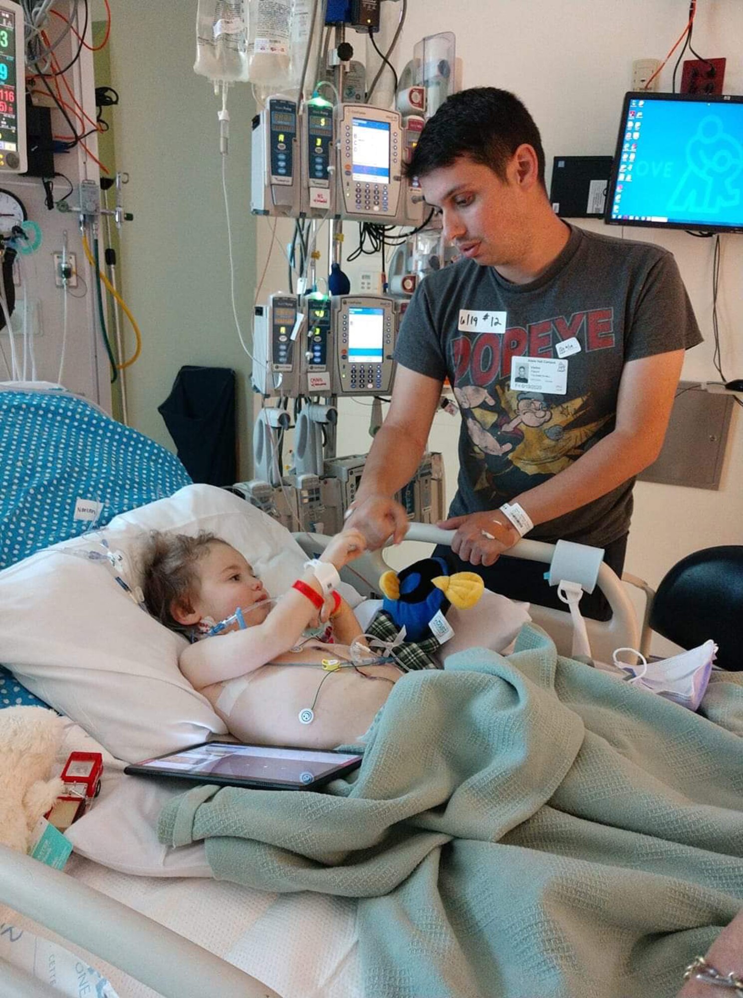 Senior Airman Anthony Gauna Jr. fist bumps with his son Anthony Gauna III in a hospital bed.