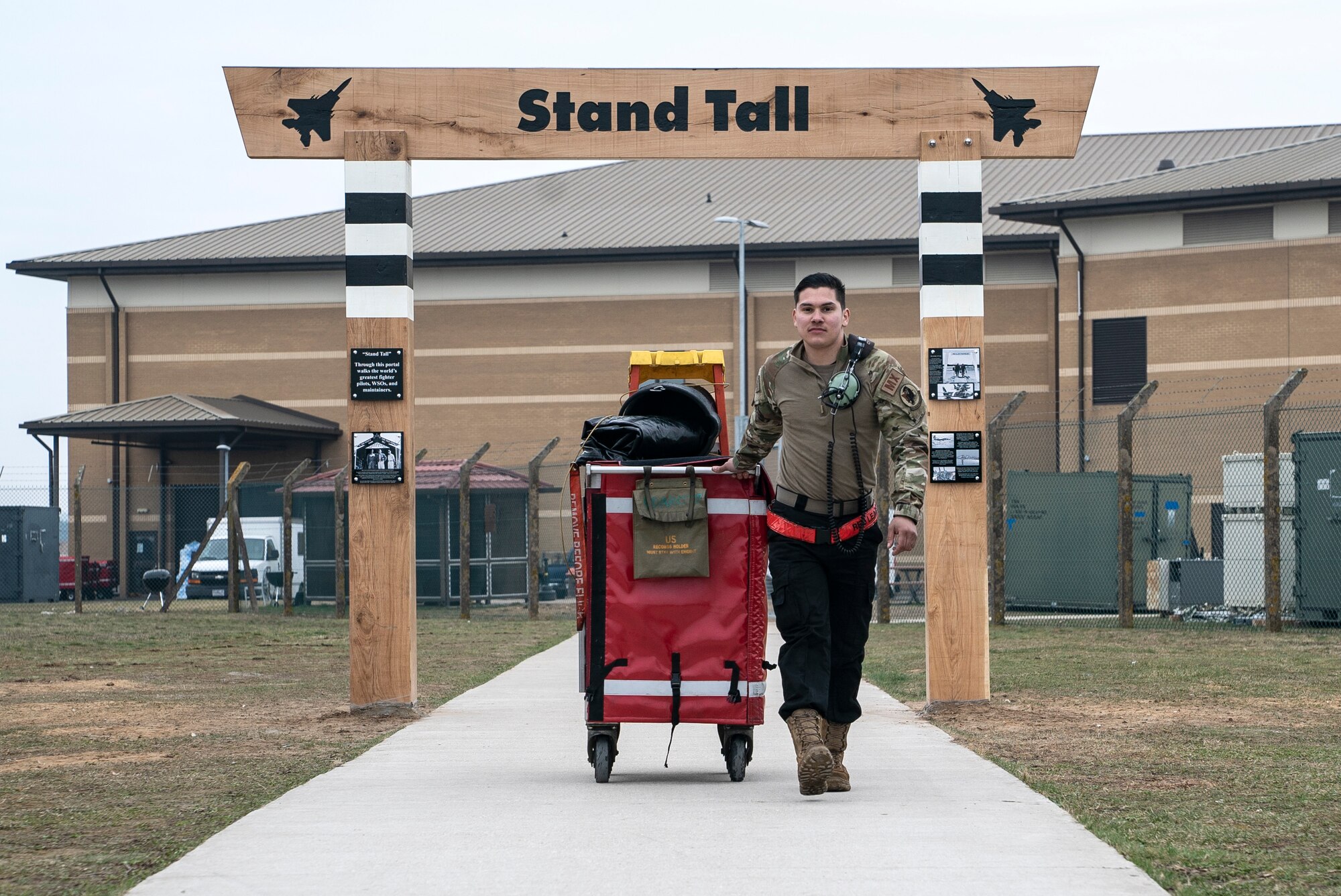 U.S. Air Force Senior Airman Justin Sanchez, 48th Aircraft Maintenance Squadron crew chief, walks under the heritage arch toward the flightline at Royal Air Force Lakenheath, England, March 8, 2021. Liberty Wing aircrew and Airmen will walk under this arch on their way to carry out the 48th Fighter Wing mission for years to come. (U.S. Air Force photo by Airman 1st Class Jessi Monte)