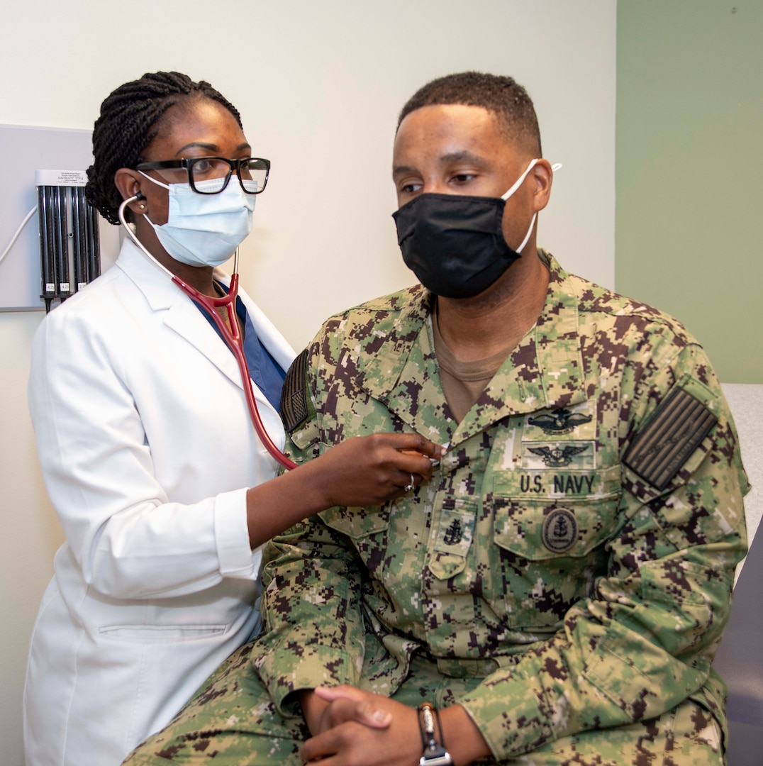 Lt. Abiola Babawale, an internal medicine intern at Naval Medical Center Portsmouth, uses a stethoscope on CMDCS Terrance Foote, the command senior chief of Virginia Military Institute, during a routine appointment.
