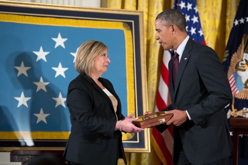 A man hands a box to a woman.