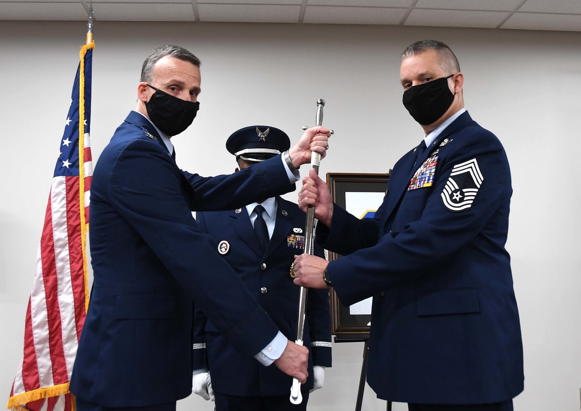 U.S. Air Force 145th Airlift Wing (AW) Command Chief Master Sgt. William R. Harper, Jr. ceremoniously accepts a sword as symbolism of taking over authority as the new Command Chief of the 145th AW during a Change of Authority Ceremony held at the North Carolina Air National Guard Base, Charlotte Douglas International Airport, March 6, 2021. CMSgt Susan A. Dietz, relinquishes authority of the 145th AW Command Chief position as CMSgt Harper, accepts authority.