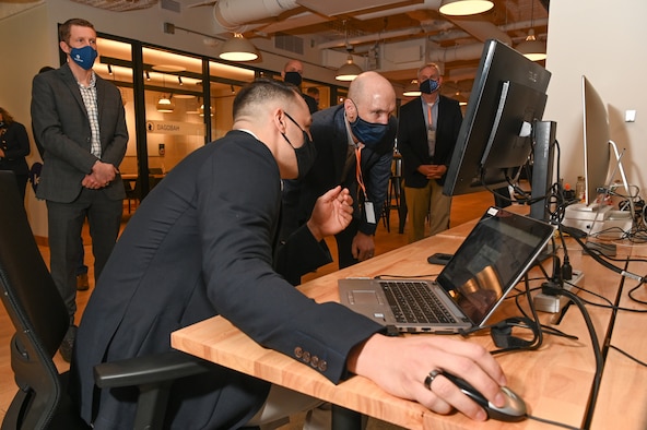 First Lt. Maurice Morrell, Command and Control Incident Management and Emergency Response deputy program manager, Air Force Life Cycle Management Center Detachment 12, provides a demonstration to Air Force Vice Chief of Staff Gen. David W. Allvin during a tour of the Det. 12, Kessel Run, headquarters in Boston, March 8, 2021, while Col. Brian Beachkofski, Det. 12 commander, looks on. (U.S. Air Force photo by Todd Maki)