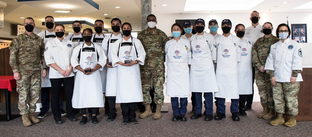 Several people stand together to have their photo taken. Some of the hold awards.