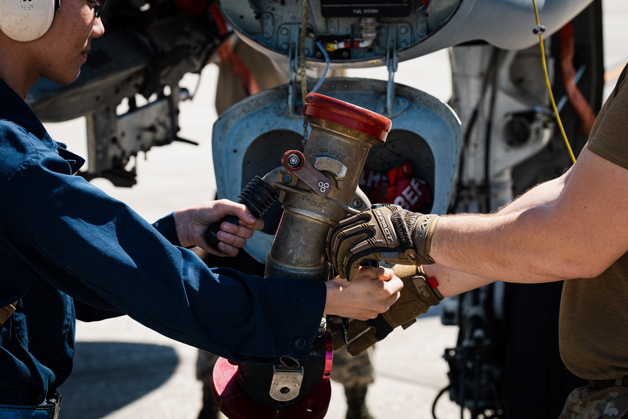 A photo of an Airman passing a fuel hose to another Airman