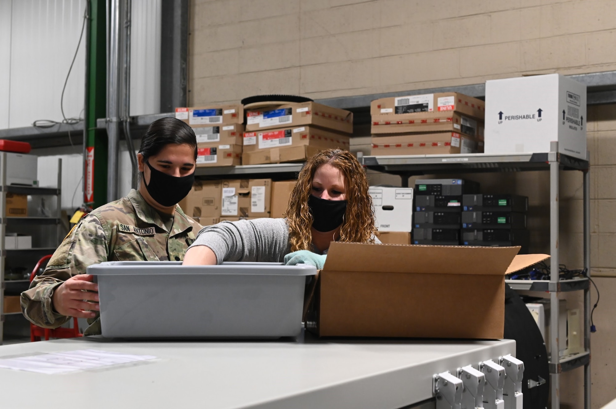 A female Army member and a woman move samples of CCP to boxes labeled "COVID-CCP"