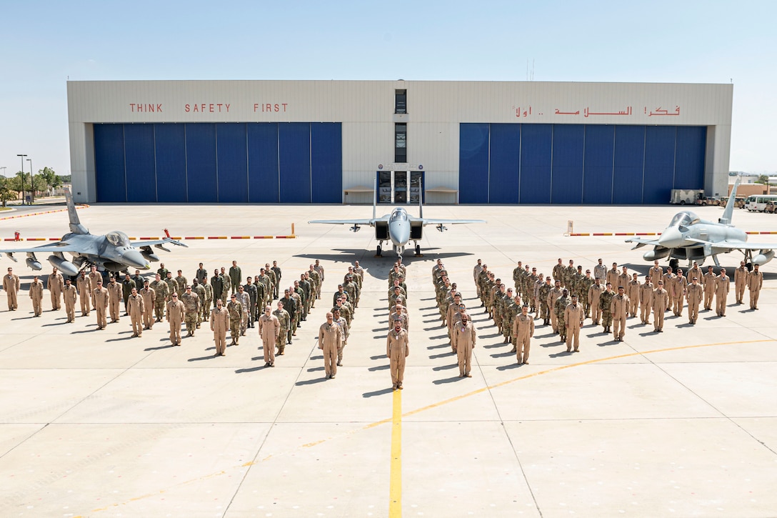 U.S. and Saudi troops line up for a photo near aircraft.