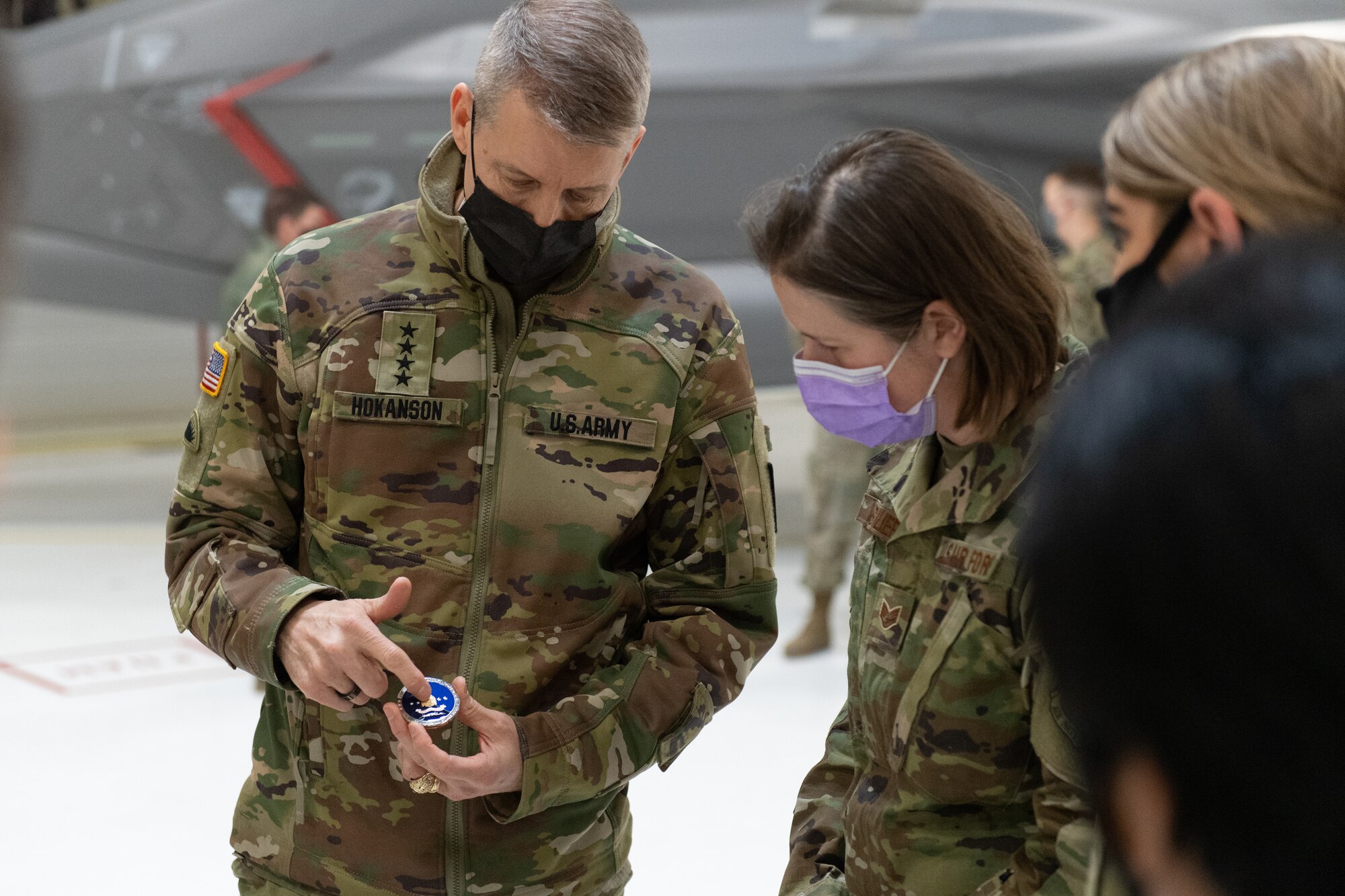 U.S. Army General Daniel R. Hokanson, chief, National Guard Bureau, describes his coin to Staff Sgt. Sarah Basiliere, Airman assigned to the 158th Fighter Wing.