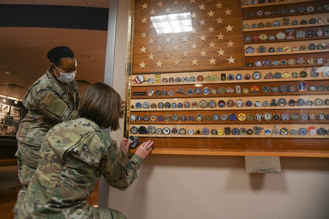 Chief Master Sgt. of the Air Force JoAnne Bass adds her coin to the American flag coin display at the Aeromedical Staging Facility, Joint Base Andrews, Md., March 4, 2021.