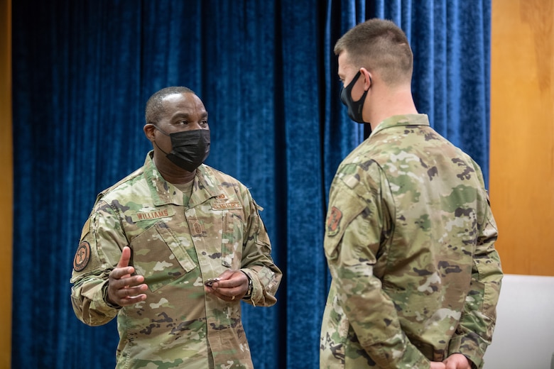 U.S. Air Force Chief Master Sgt. Maurice L. Williams, command chief, Air National Guard (ANG), presents a coin to an Airman assigned to the 158th Fighter Wing.