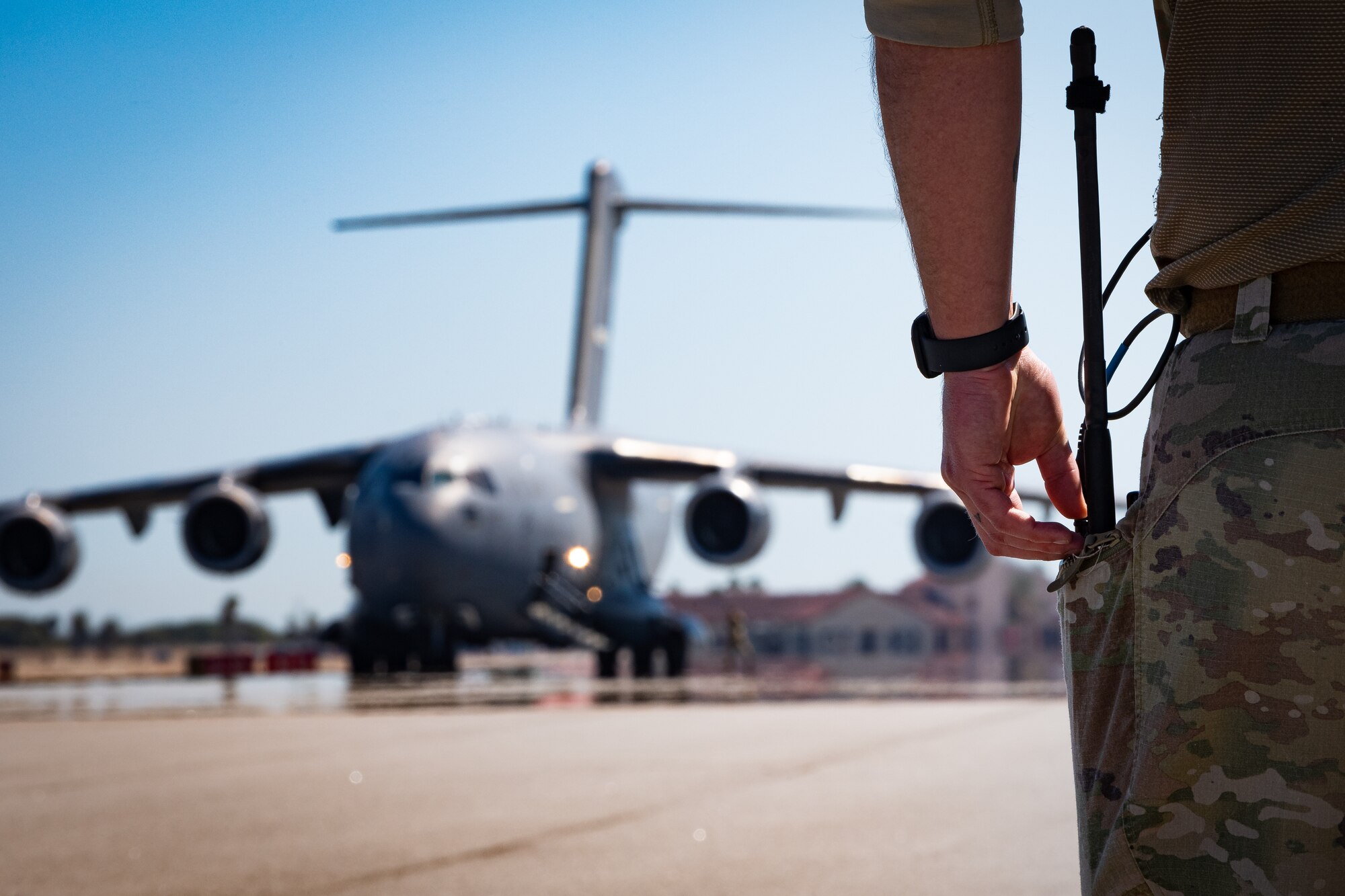 A photo of an Airman waiting for an Aircraft to taxi in