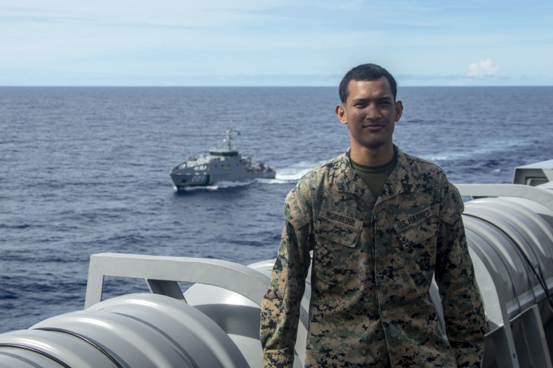 U.S. Marine Corps Cpl. Tommy Ngirbedul Jr., a native of Palau and radio operator with 31st Marine Expeditionary Unit (MEU), stands in front of patrol boat PSS President H.I. Remeliik II with Palau Bureau of Maritime Security after acting as translator during a joint ship formation in order to facilitate better communication aboard USS New Orleans (LPD 18) off the coast of Palau, Feb. 27, 2021.