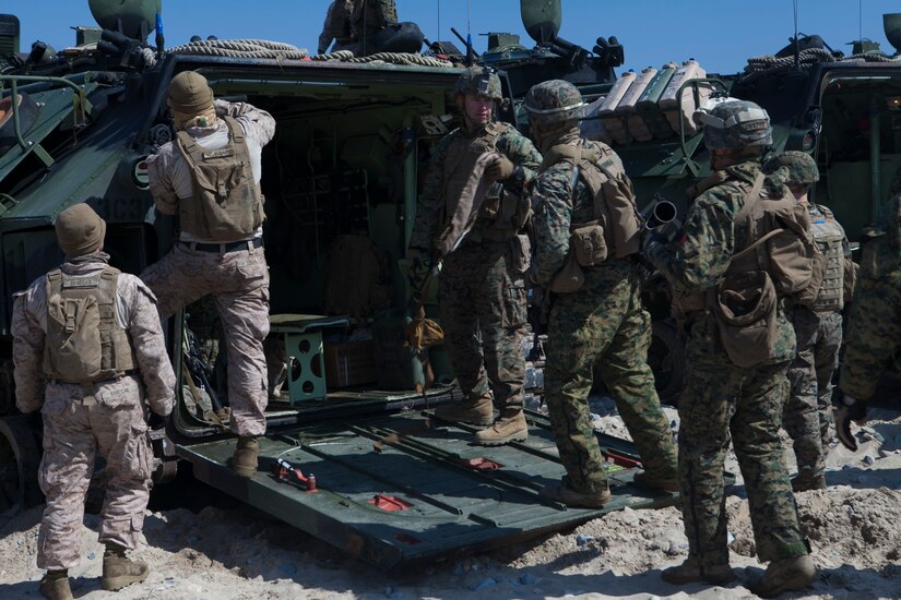 Service members gather around the rear opening of a combat vehicle.